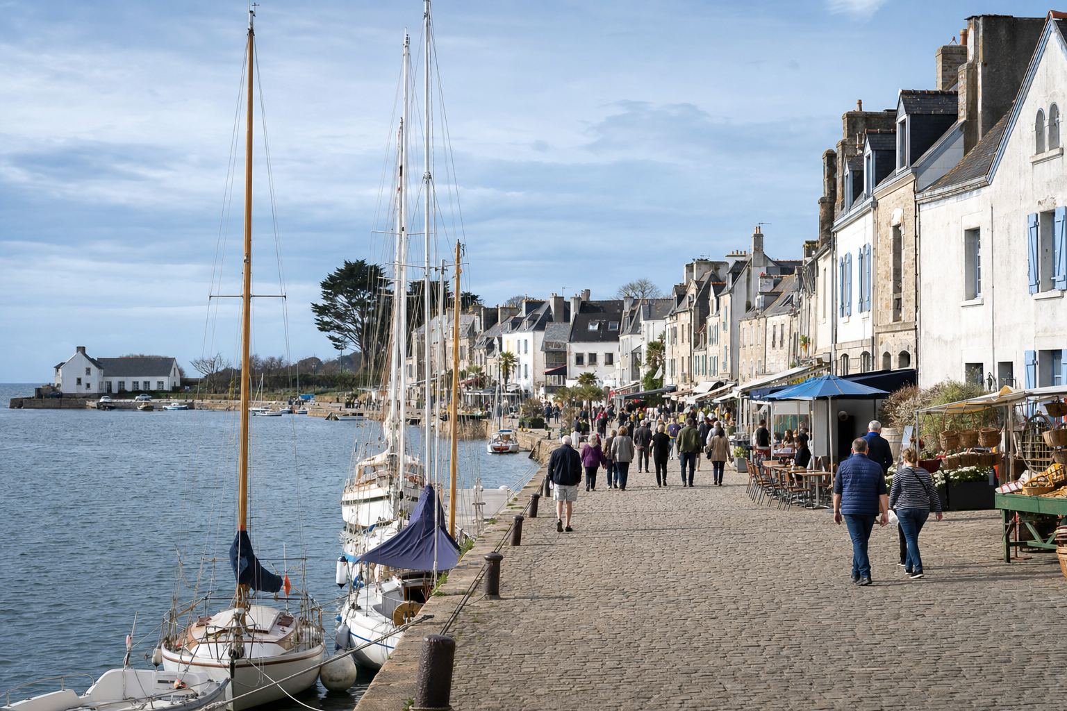 Front de quai animé face aux voiliers amarrés, commerces et terrasses au bord du bassin