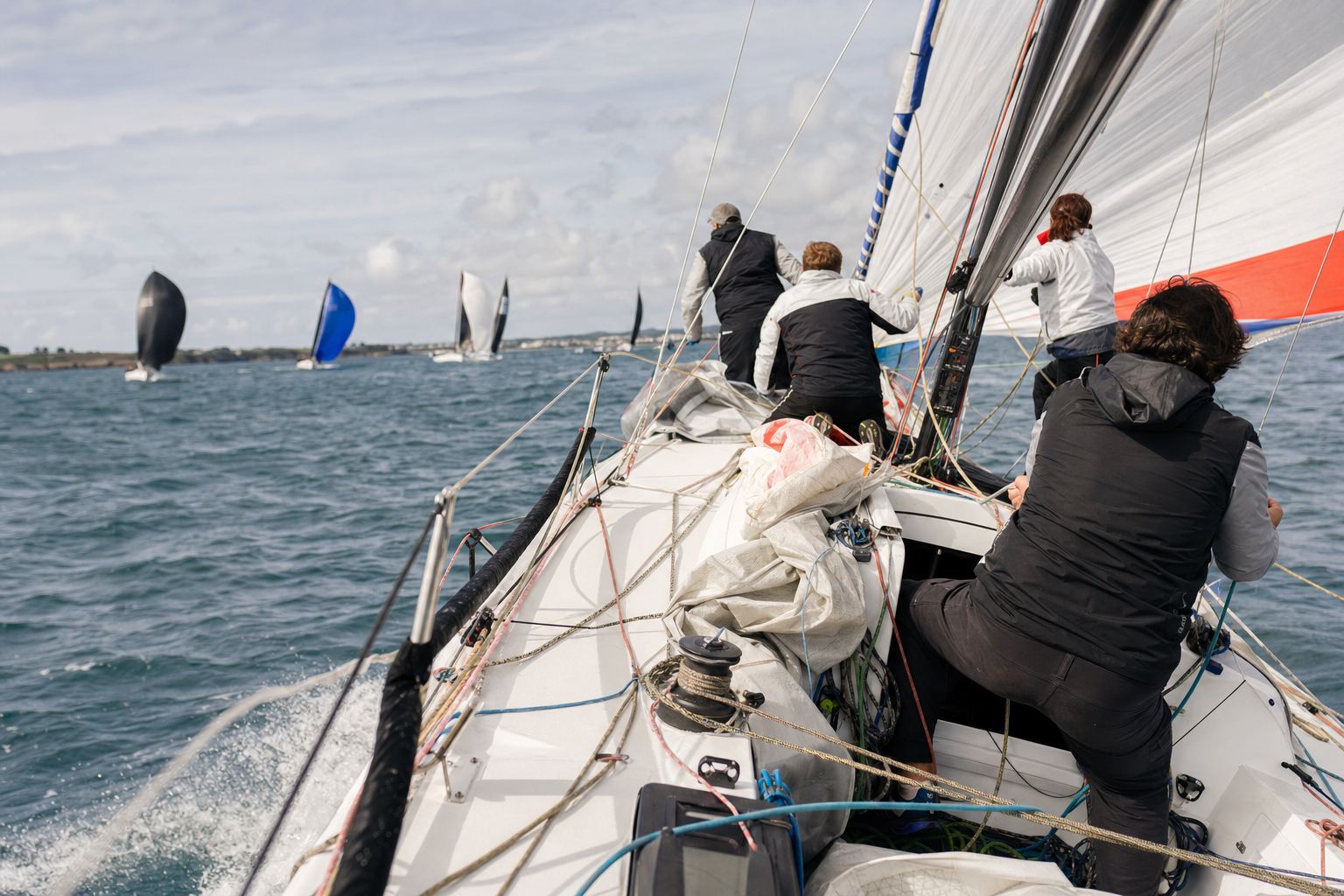 Équipage à la manœuvre sur la plage avant d'un quillard de course pendant un envoi de spi