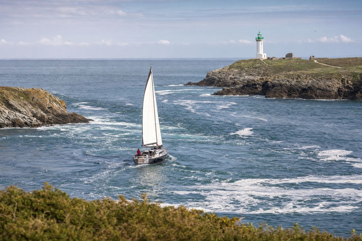 Voilier négociant le goulet du Golfe du Morbihan dans le courant, phare en arrière-plan