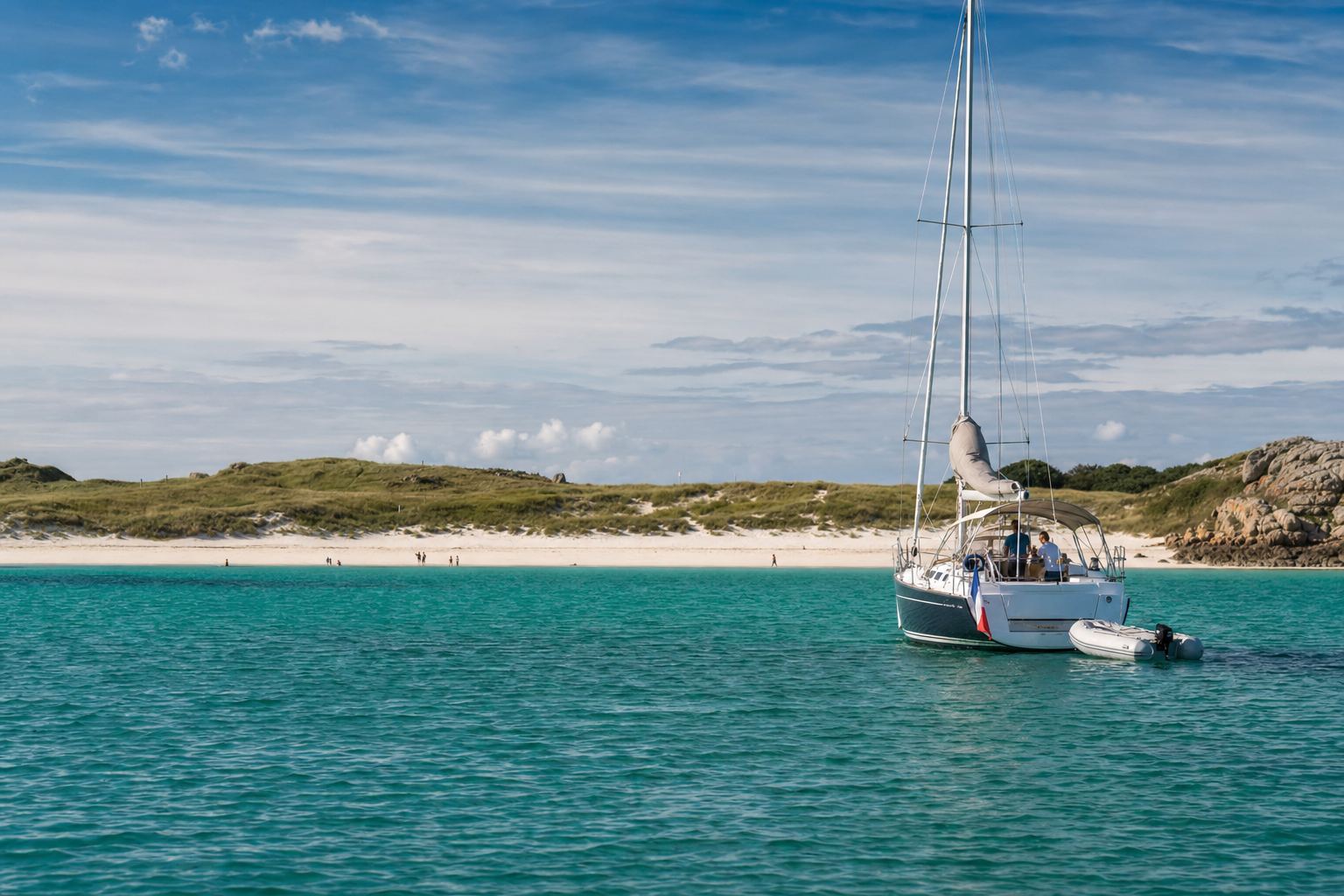 Voilier au mouillage devant une plage de sable blanc en Bretagne Sud