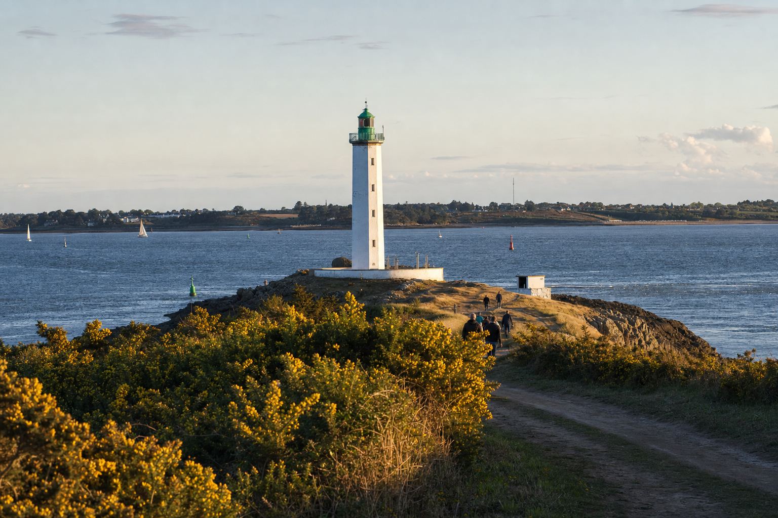 Phare blanc à lanterne verte sur la pointe rocheuse au soleil couchant